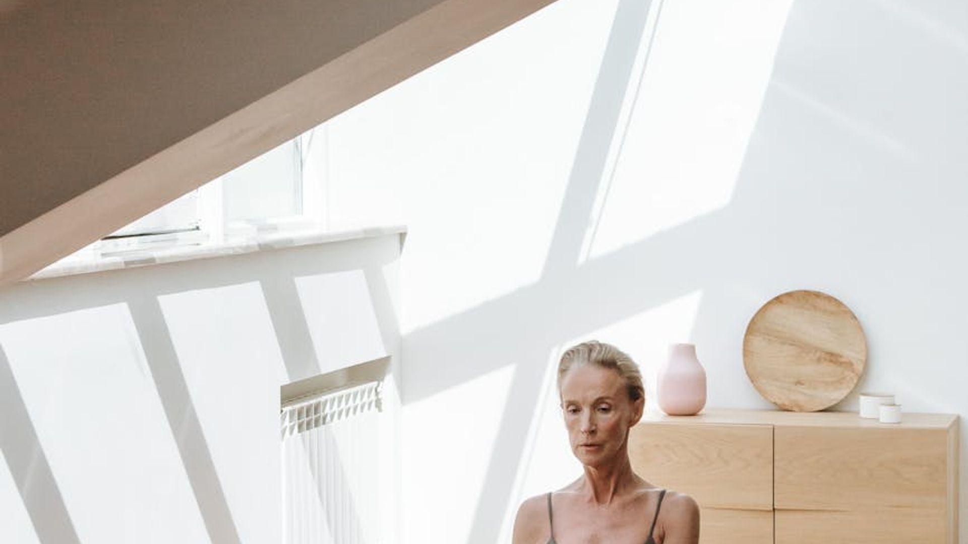 Calm woman practicing yoga in a serene, minimalist environment.